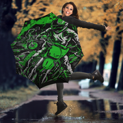 A woman jumps in a puddle holding a large open umbrella printed with a green and black motorcycle graphic, set against a blurred autumn street background.