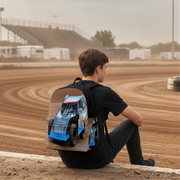 A kid sitting on a dirt track wearing a black backpack with a printed racing car design, with the racetrack in the background.