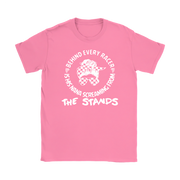 A pink short-sleeve crewneck t-shirt with a white graphic print on the front. The graphic features a cartoon horse with a checkered pattern and a racing flag, surrounded by the text 'BEHIND EVERY RACER IS HIS NANA SCREAMING FROM THE STANDS'.