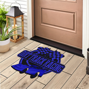 A blue and black drift track racing doormat placed on a light wood porch floor in front of a brown door, with a lantern and potted plant nearby.