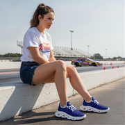 Woman sitting on a track wearing blue sneakers with a car in the background