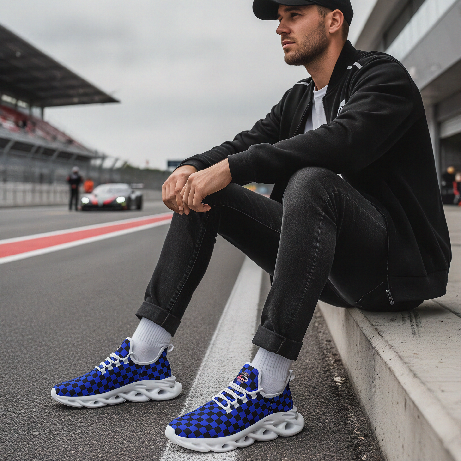 Man sitting on a race track wearing blue checkered sneakers