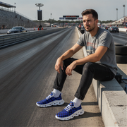 Man sitting on a race track wearing blue checkered sneakers