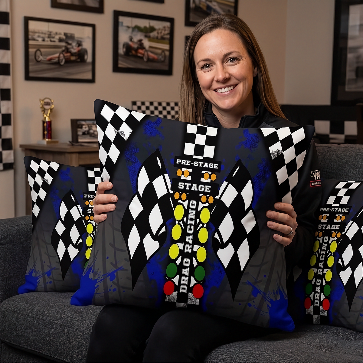 a Woman sitting on a sofa in a themed drag racing room holding a drag racing pillow with big DRAG RACING Christmas tree