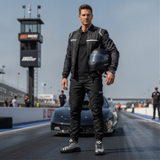 Man in racing gear holding a helmet on a race track wearing checkered shoes with a tower in the background