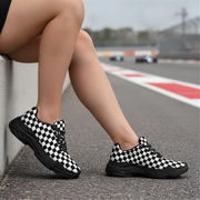 Person wearing black and white checkered shoes on a race track.