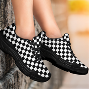 Black and white checkered sneakers worn by a person against a blurred natural background