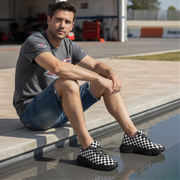 Man sitting by a pool wearing checkered shoes in an outdoor setting