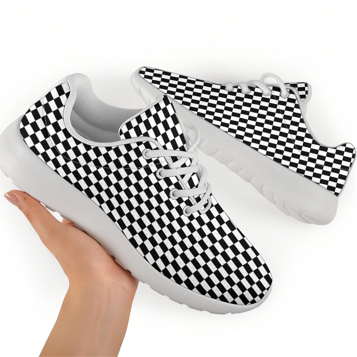 Hand holding a black-and-white checkered sneaker with white laces and sole, with the matching shoe behind it.