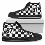 A pair of high-top sneakers with a black rubber sole and laces, featuring a beige and brown geometric Southwestern-style pattern on the canvas uppers, displayed on and around a white shoebox against a white background.