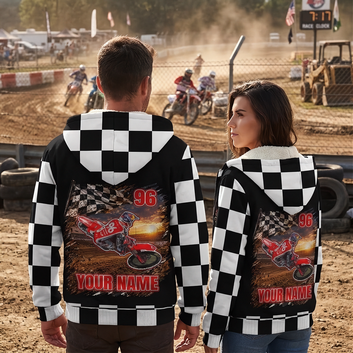 Couple wearing personalized dirt bike sherpa jackets at a motocross track, showing matching rider artwork, number 96, and name designs.