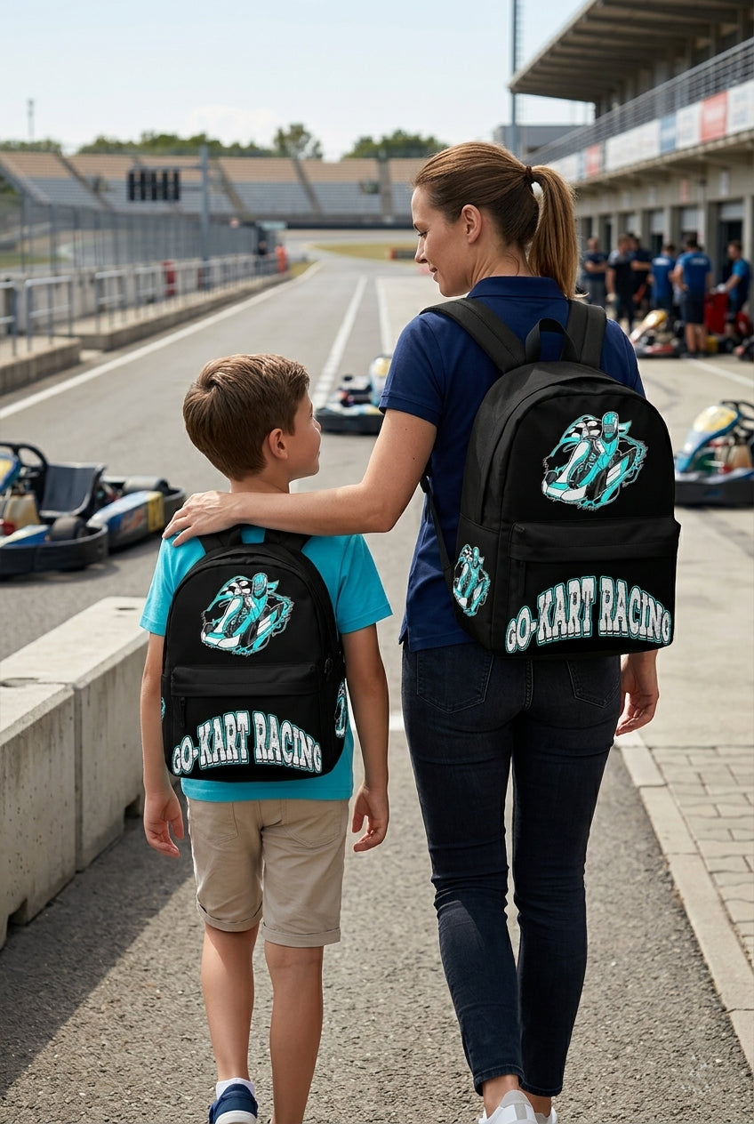 A young boy wearing a Carolina Blue go-kart racing backpack, walking alongside an adult woman toward an outdoor asphalt karting circuit on a bright, sunny afternoon.