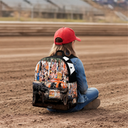 a little girl wearing a custom demolition derby backpack sitting in a dirt track