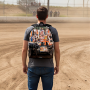 A man viewed from behind wearing a gray t-shirt and blue jeans, carrying a backpack on his back. The backpack features a graphic print of an orange and white Demolition derby car with a crowd of spectators in the background.