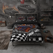 A racing-themed bedding set featuring a blue and orange race truck on a black and gray tire-track background with checkered flags and the words 'Demolition derby'. The set is displayed on a metal bed frame in a styled room with a gray concrete floor, a gray wall with car sketches, and racing props.