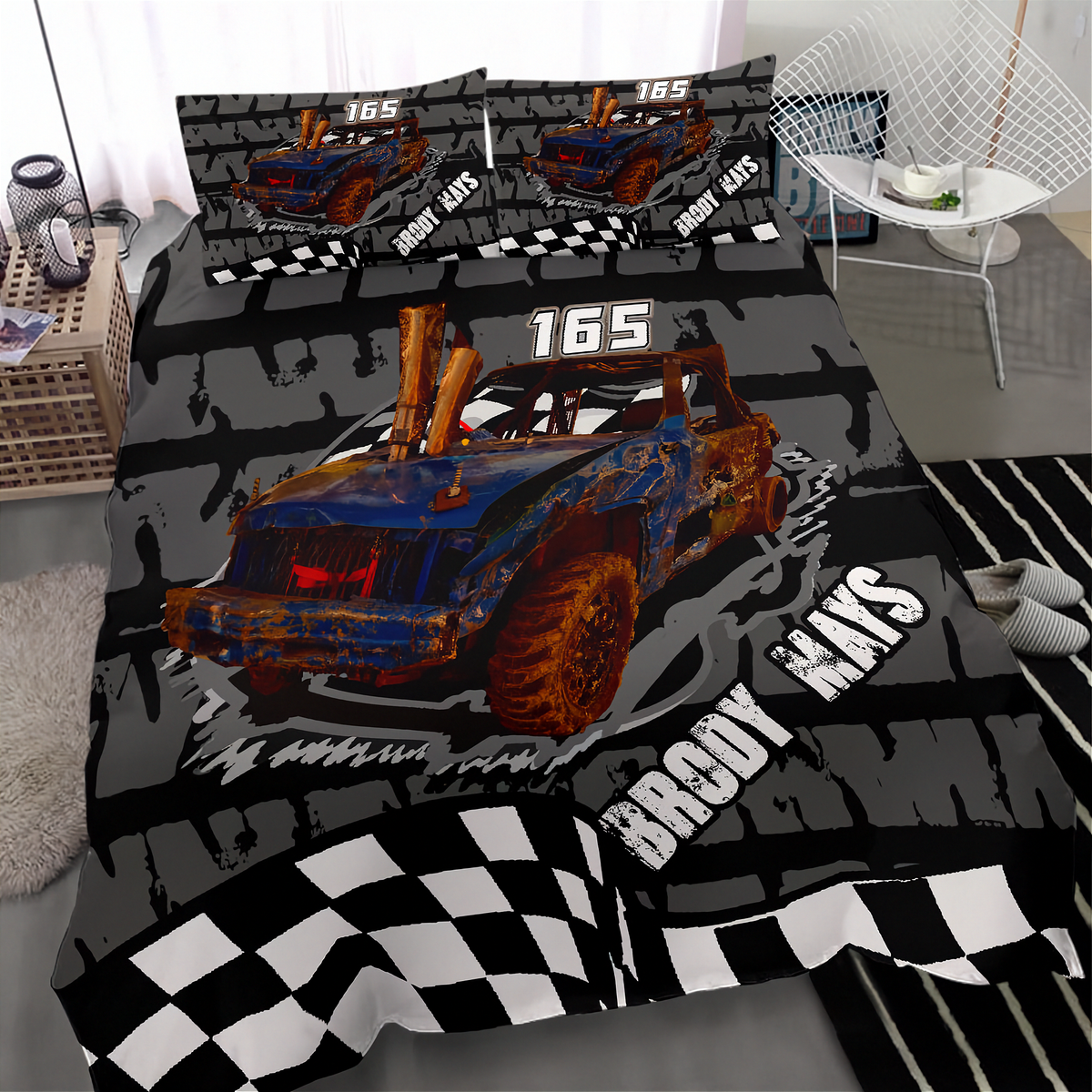 A bed dressed in a racing-themed bedding set featuring a blue and rusted orange off-road truck graphic, black and gray tire tracks, the number 165, and checkered flag patterns. The set includes a duvet cover and two matching pillowcases, shown in a styled bedroom setting.
