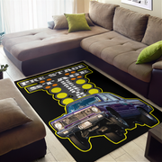 A rectangular area rug featuring a graphic design of a purple classic car and the words 'PRE-STAGE ZONE' on a black background, styled in a living room setting on a light wood floor next to a brown sectional sofa.
