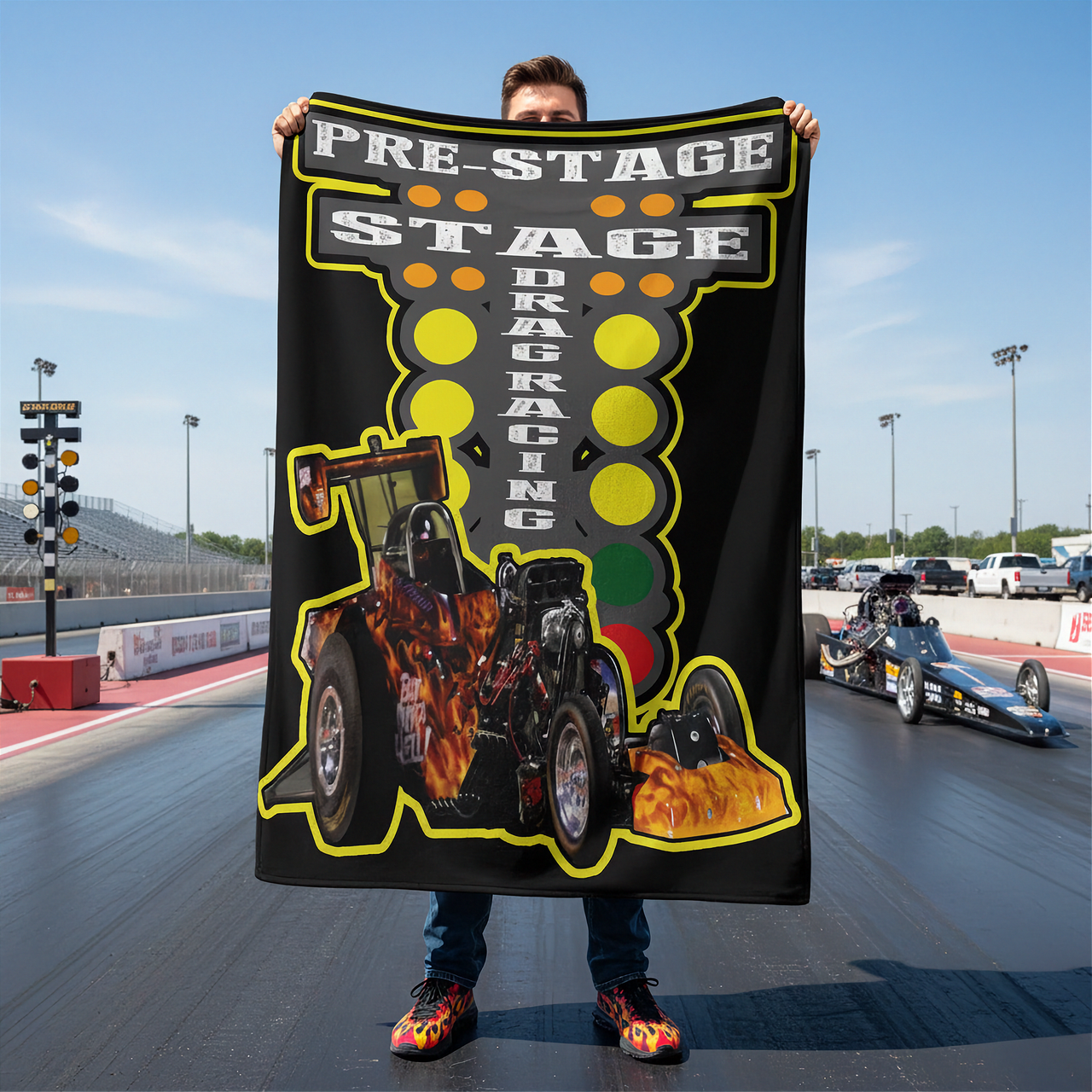 Person holding a custom 'Pre-Stage Stage Drag Racing' blanket on a race track with drag cars in the background.