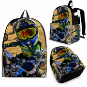 A backpack shown from multiple angles on a white background, featuring a full-color printed graphic of a motocross rider in a helmet and suit riding a dirt bike on a sandy track.