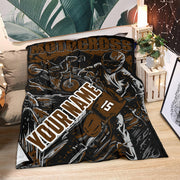 Brown and black personalized motocross blanket spread across a couch beside plants and lanterns, with sample number 15.