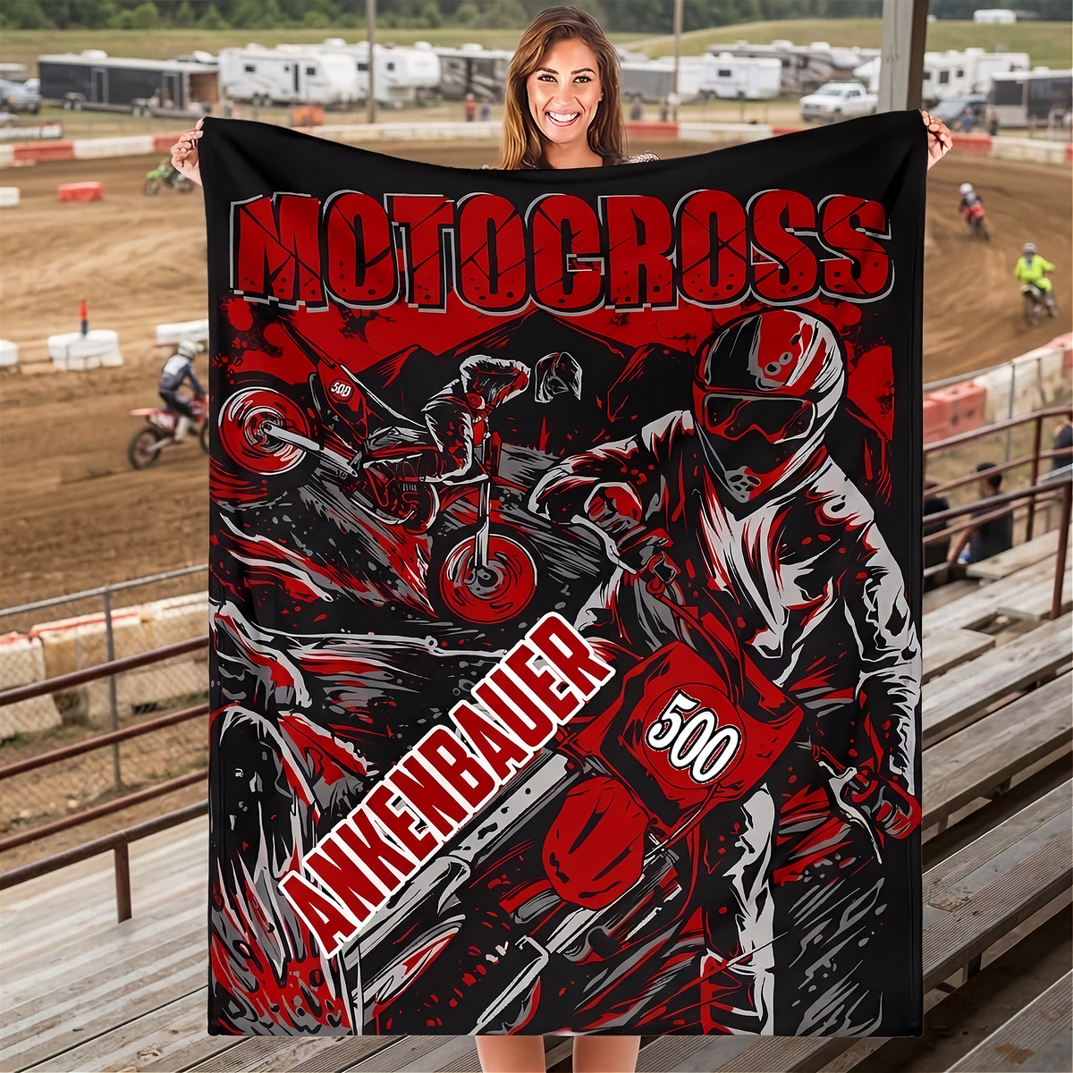 Woman holding a red and black personalized motocross blanket with sample name and number 500 in trackside bleachers.