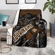 Brown and black custom motocross blanket over a gray couch beside a round table, with sample name and number 15.