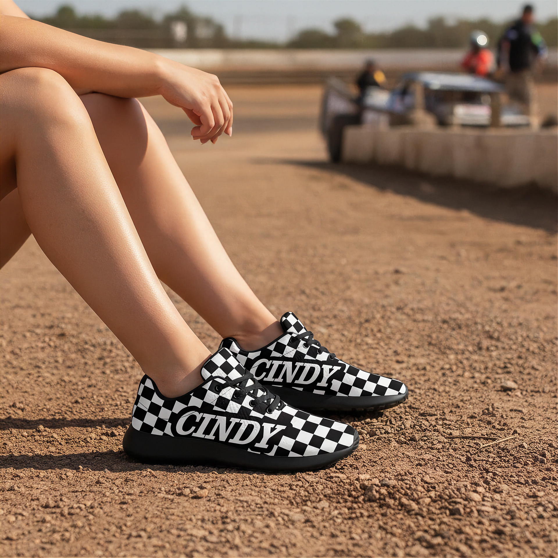 Woman wearing black and white checkered shoes with 'CINDY' branding on a dirt track.