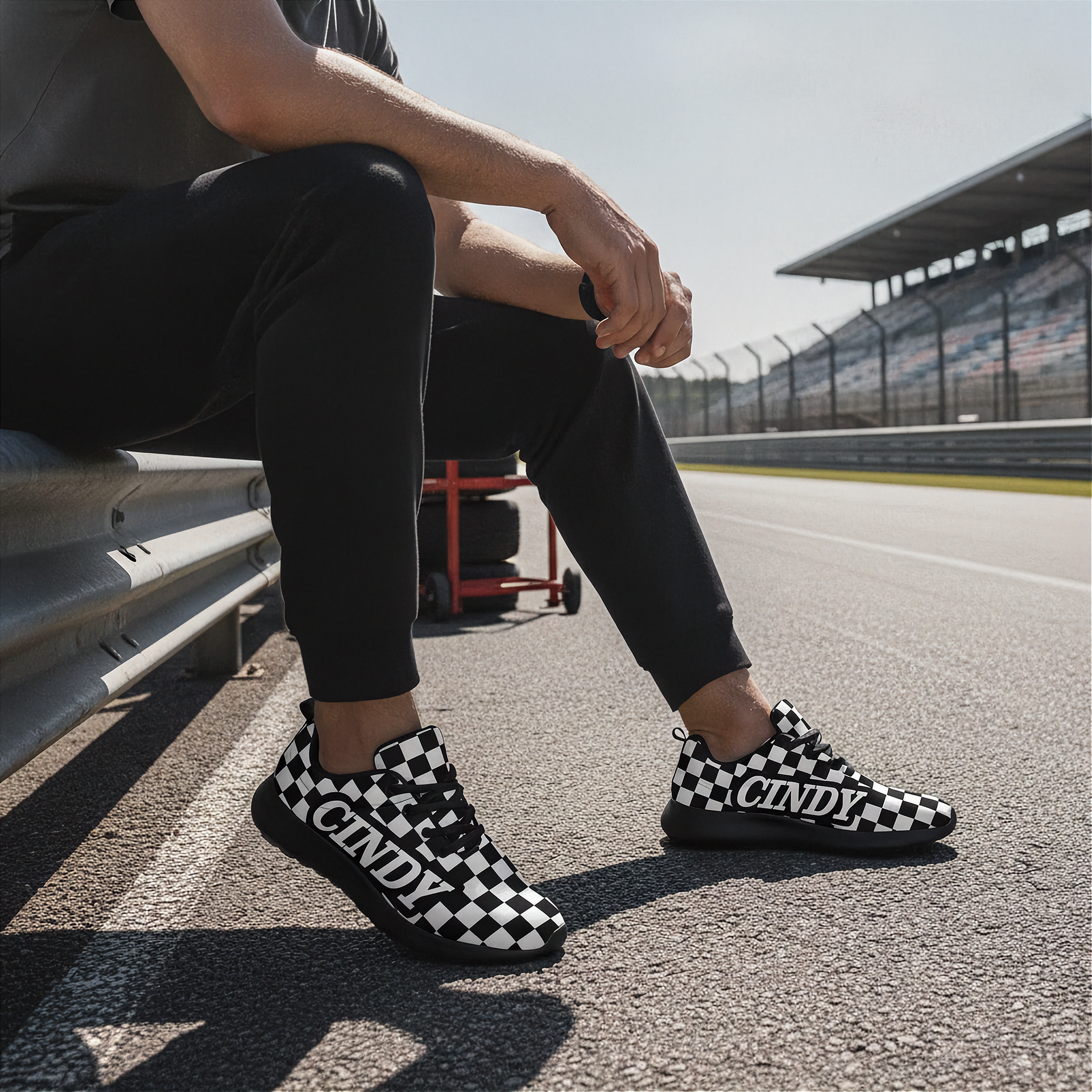 Man wearing black and white checkered shoes with 'CINDY' branding on a race track.