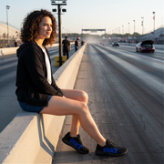 Woman sitting on a race track with cars in the background