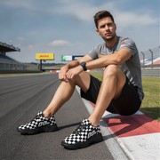Man sitting on a race track wearing checkered shoes