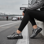 Person wearing black and white checkered shoes on a race track.