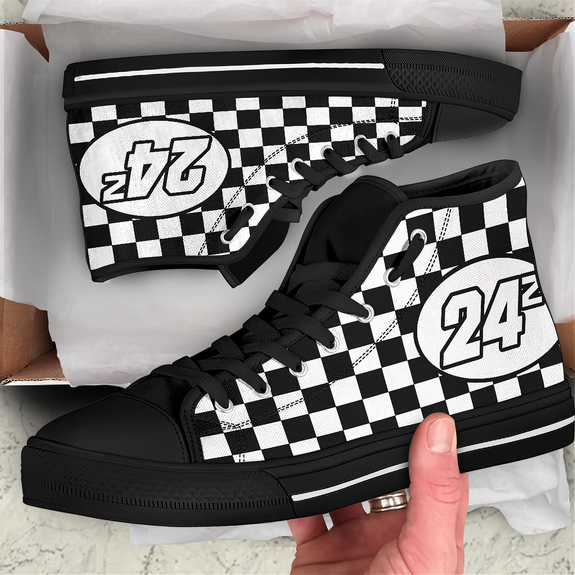 Black and white checkered high-top sneakers with number 24 design, held by a hand.
