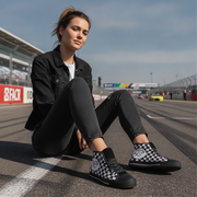 Woman sitting on a race track wearing checkered shoes
