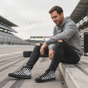 Man sitting on a race track wearing checkered shoes