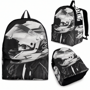A black backpack shown from multiple angles on a white background, featuring a grayscale racing helmet and rider print. The backpack has black straps, a top handle, a front zip pocket, and a side pocket with a white vertical text accent.