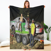 Woman holding a blanket with a printed image of a man and woman by a truck.