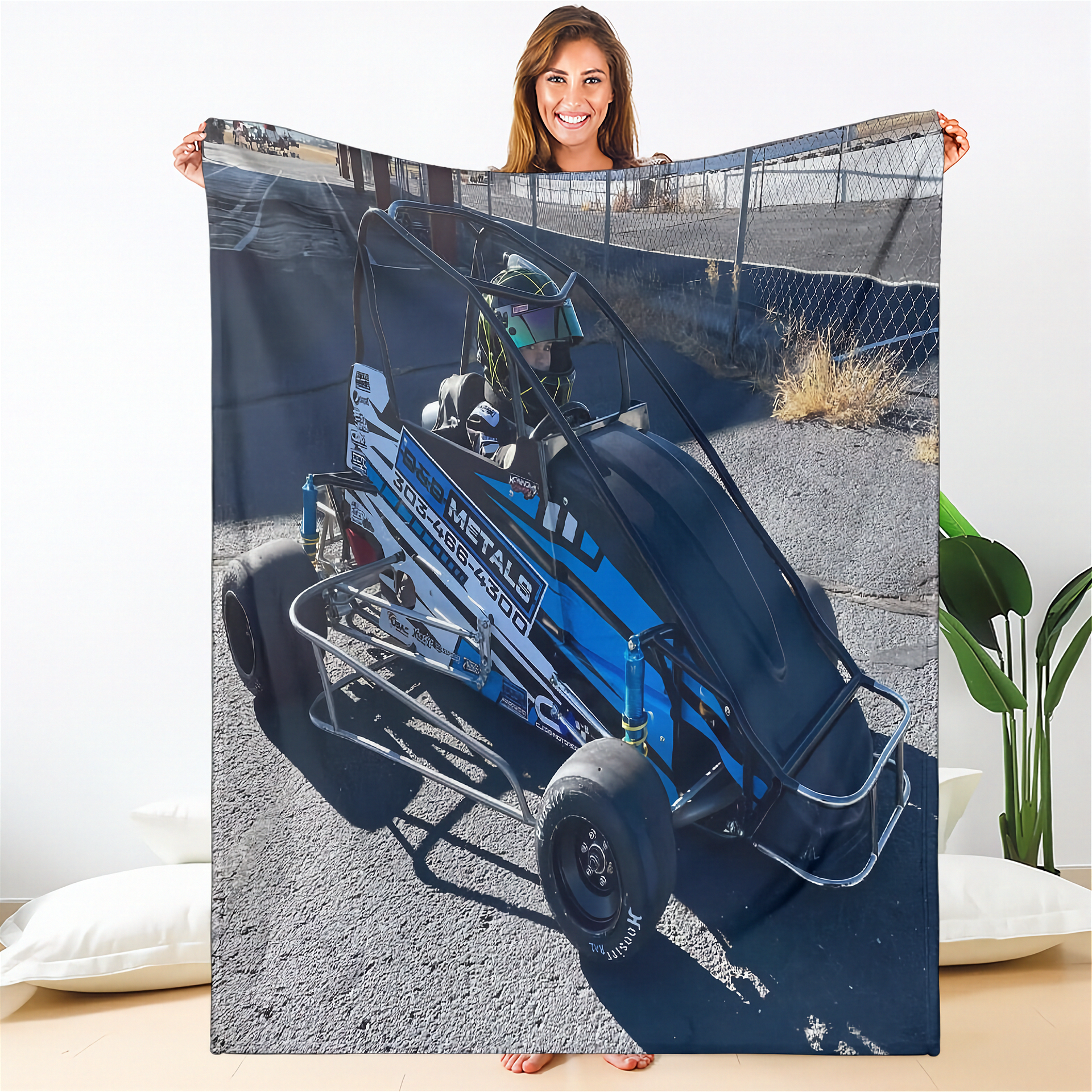 Person holding a blanket with a blue go-kart design on a white background