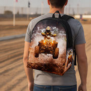 A man viewed from behind wearing a gray t-shirt and blue jeans, carrying a backpack with a detailed graphic print of an ATV rider on a dirt track.