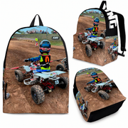 A backpack-style bag shown from multiple angles on a white background, printed with a motocross scene featuring a rider on a quad bike over a dirt track. The bag has black side panels and black straps, with a large white 'FXR' logo visible on one view.
