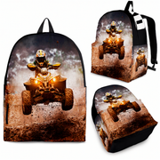 A backpack shown from multiple angles on a plain white background, featuring a printed all-terrain vehicle scene with a rider jumping over a muddy obstacle. The backpack itself is black with a large rectangular front print and black straps.