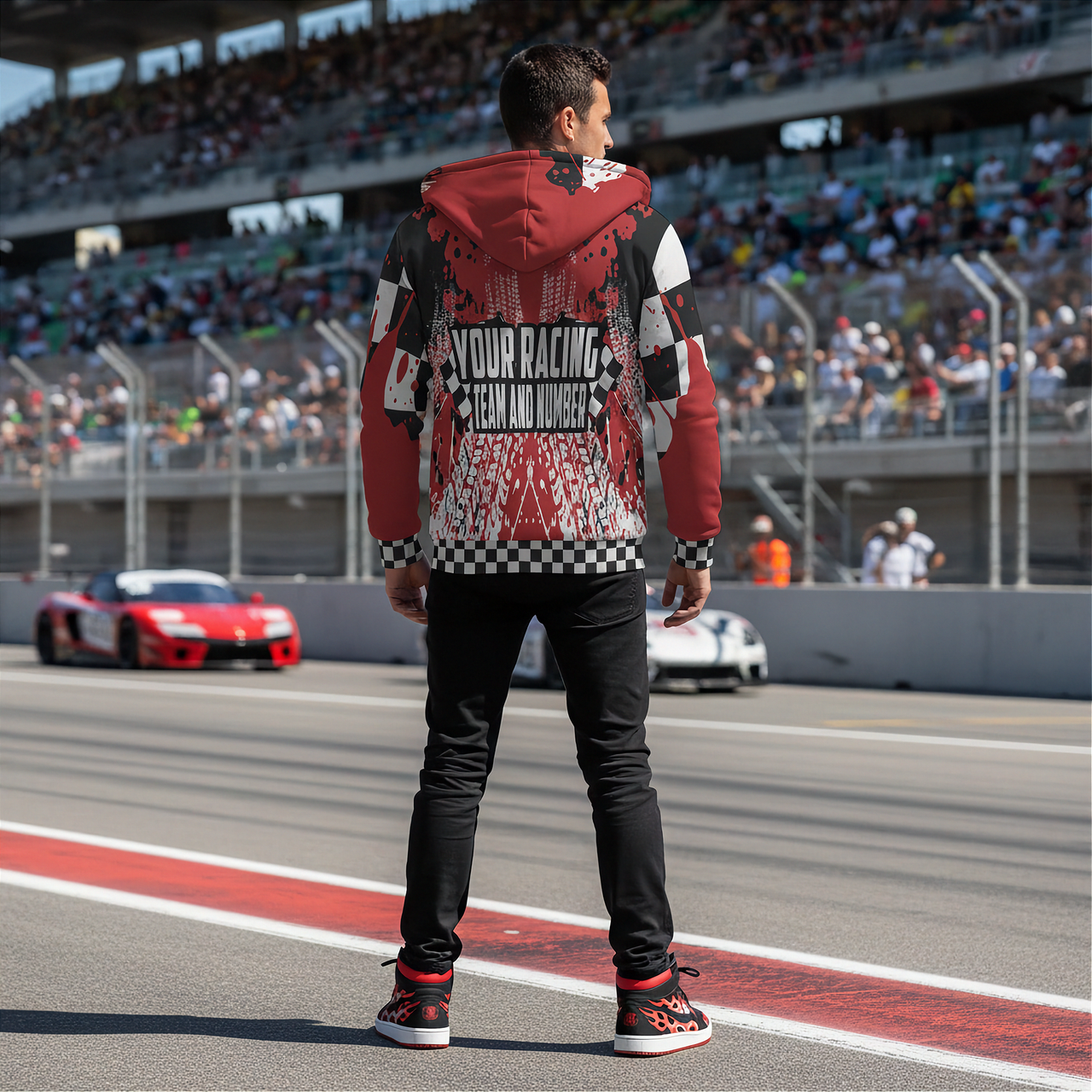Person wearing a custom racing-themed hoodie on a race track with cars and spectators in the background