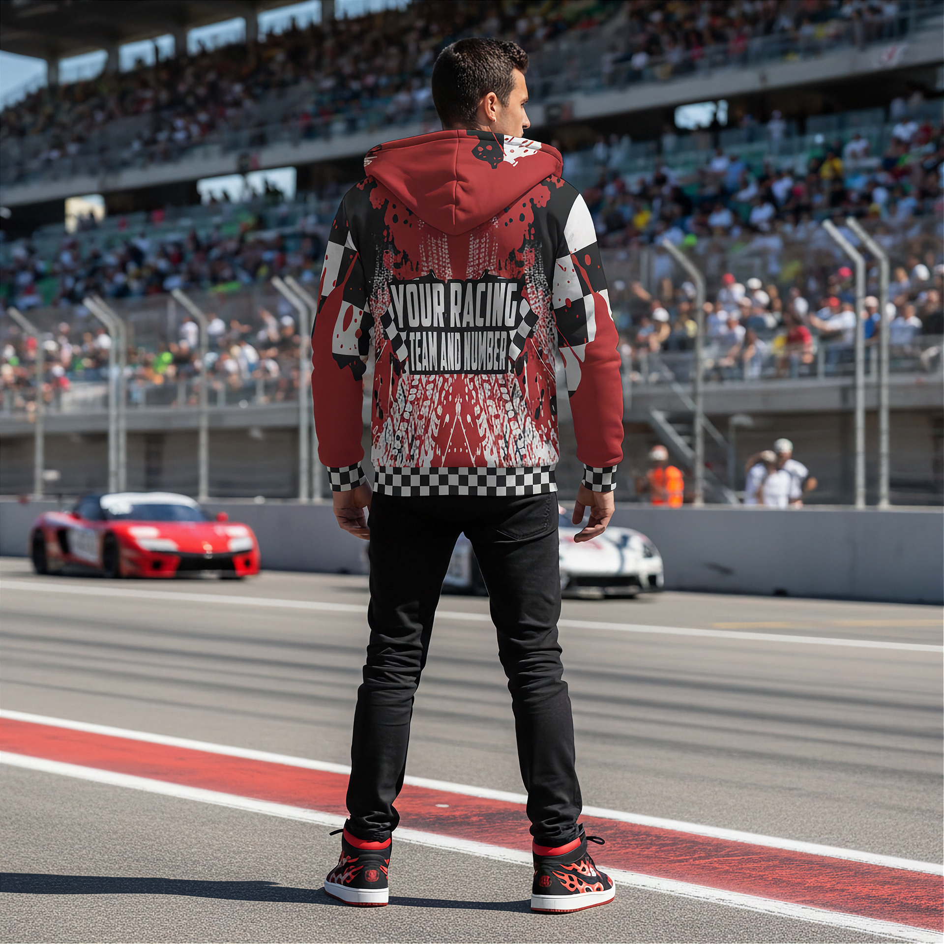 Person wearing a custom racing-themed hoodie on a race track with cars and spectators in the background