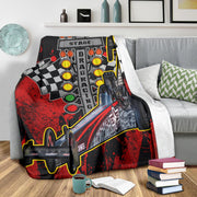 Custom dragster photo blanket on a gray sofa beside patterned cushions, with its white backing visible.