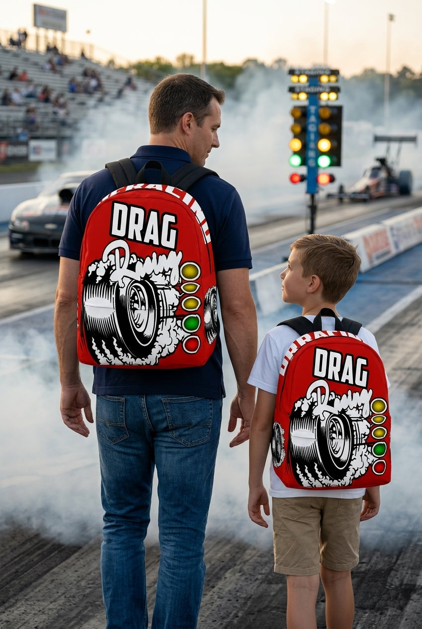 An adult man and an 8 to 12 year old child walking side by side down a drag strip lane toward the staging lights, both wearing matching custom red drag racing track backpacks viewed from behind.