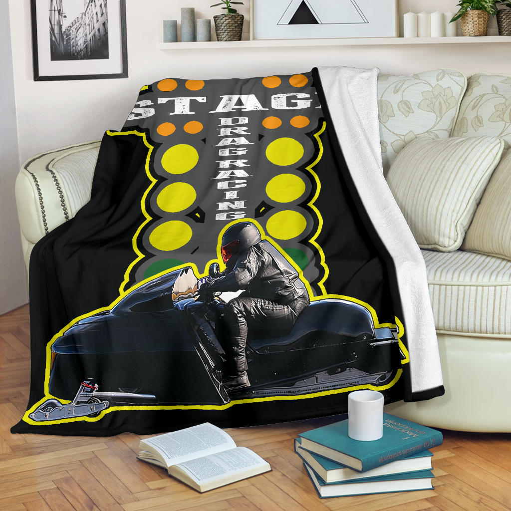 Custom snowmobile drag racing blanket draped over a cream sofa, with one edge folded back to reveal white microfleece backing.