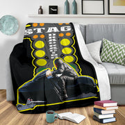 Custom snowmobile racing blanket on a gray sofa, showing the sled-and-rider design and white backing along the folded edge.