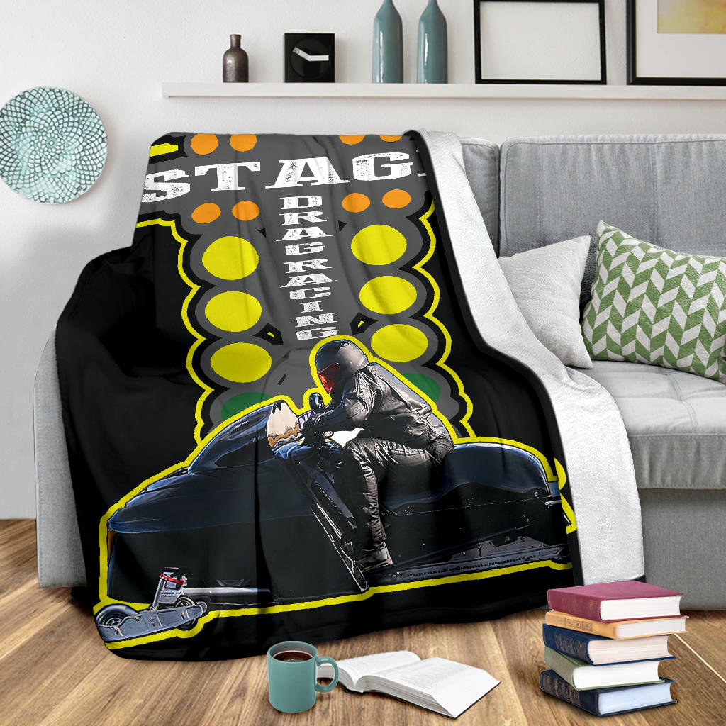 Custom snowmobile racing blanket on a gray sofa, showing the sled-and-rider design and white backing along the folded edge.
