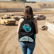 A woman seen from behind wearing a black backpack with a turquoise car graphic and 'DEMOLITION DERBY' text, standing on a dirt racetrack with race cars blurred in the background.