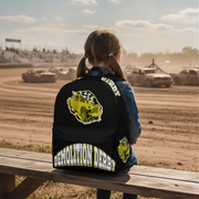 A girl with pigtails sits on a wooden bench at a dirt track, viewed from behind, wearing a black backpack with a large yellow and white Demolition Derby graphic.
