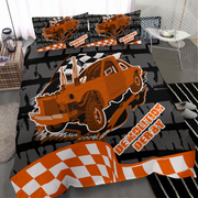 A bedding set featuring a cartoon-style orange demolition derby car on a black and gray brick-patterned background, with orange-and-white checkered stripes and the words 'Demolition Derby.' The set is shown on a bed in a bedroom setting with a chair, side table, and rug visible.